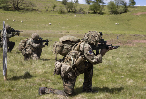 Soldier with rifle kneeling on one knee in camouflage